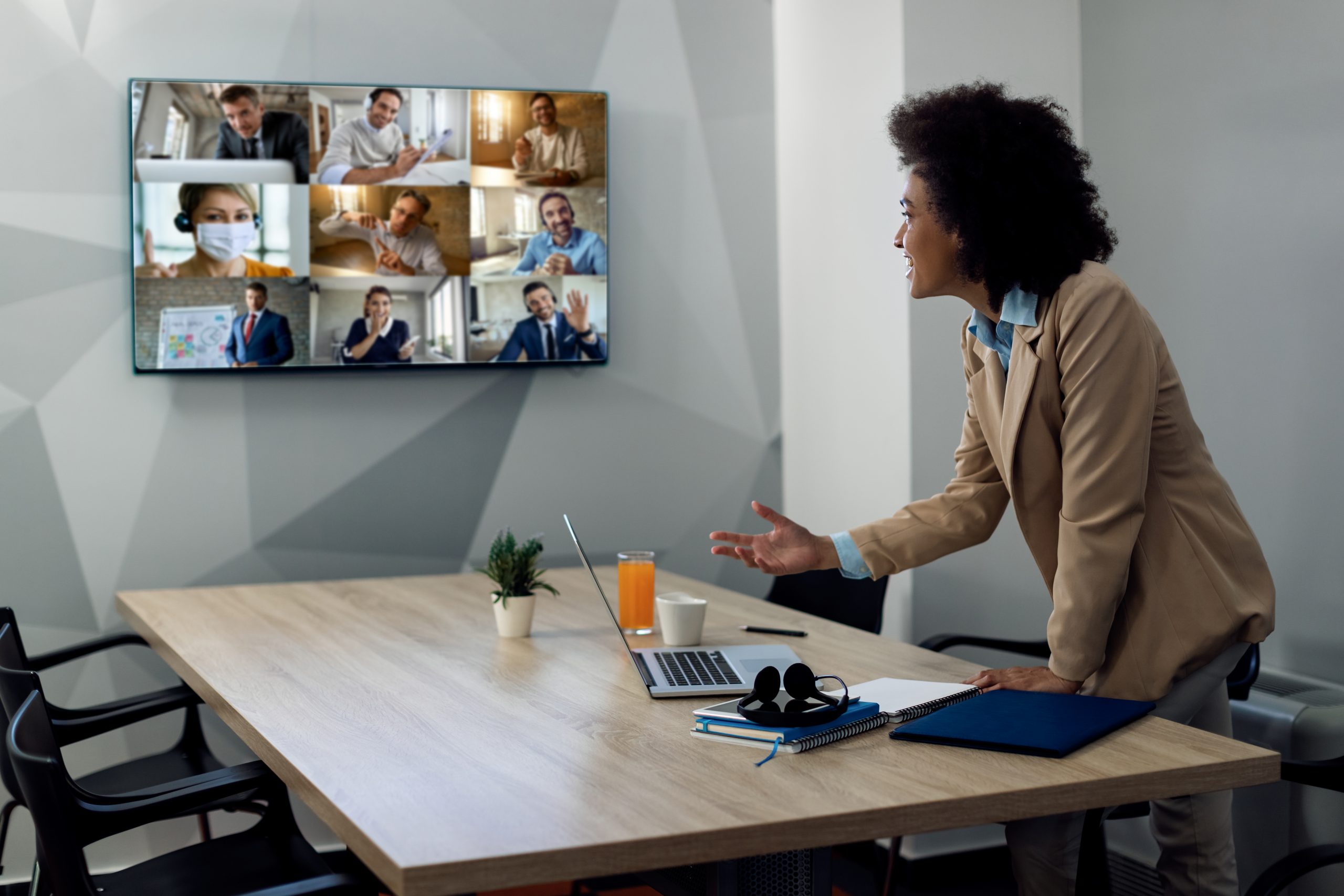 Happy black entrepreneur having online business meeting with colleagues from her office. Eine Person in einer Viko im Huddle Room