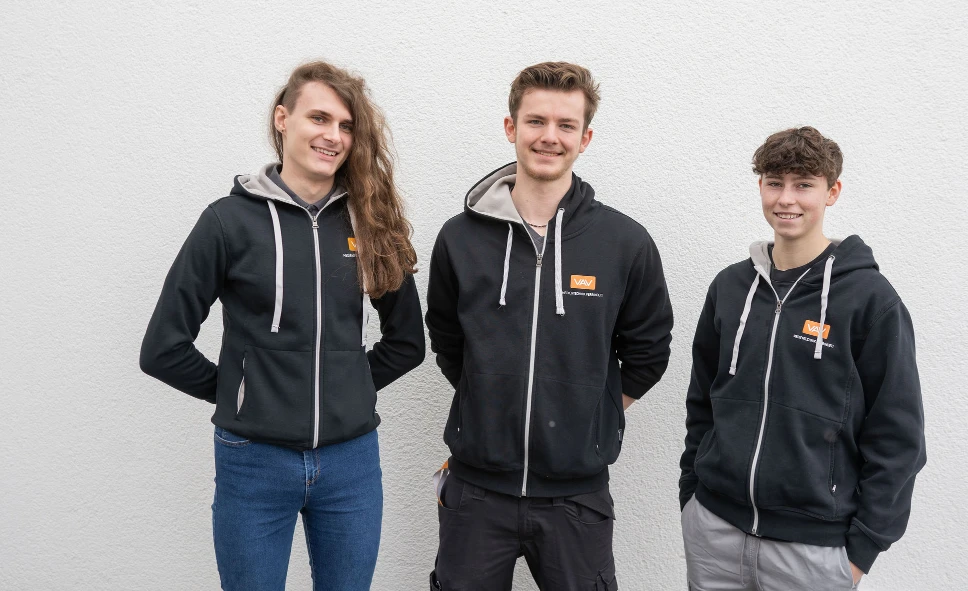 Unsere drei Auszubildenden stehen nebeneinander und lächeln in die Kamera.